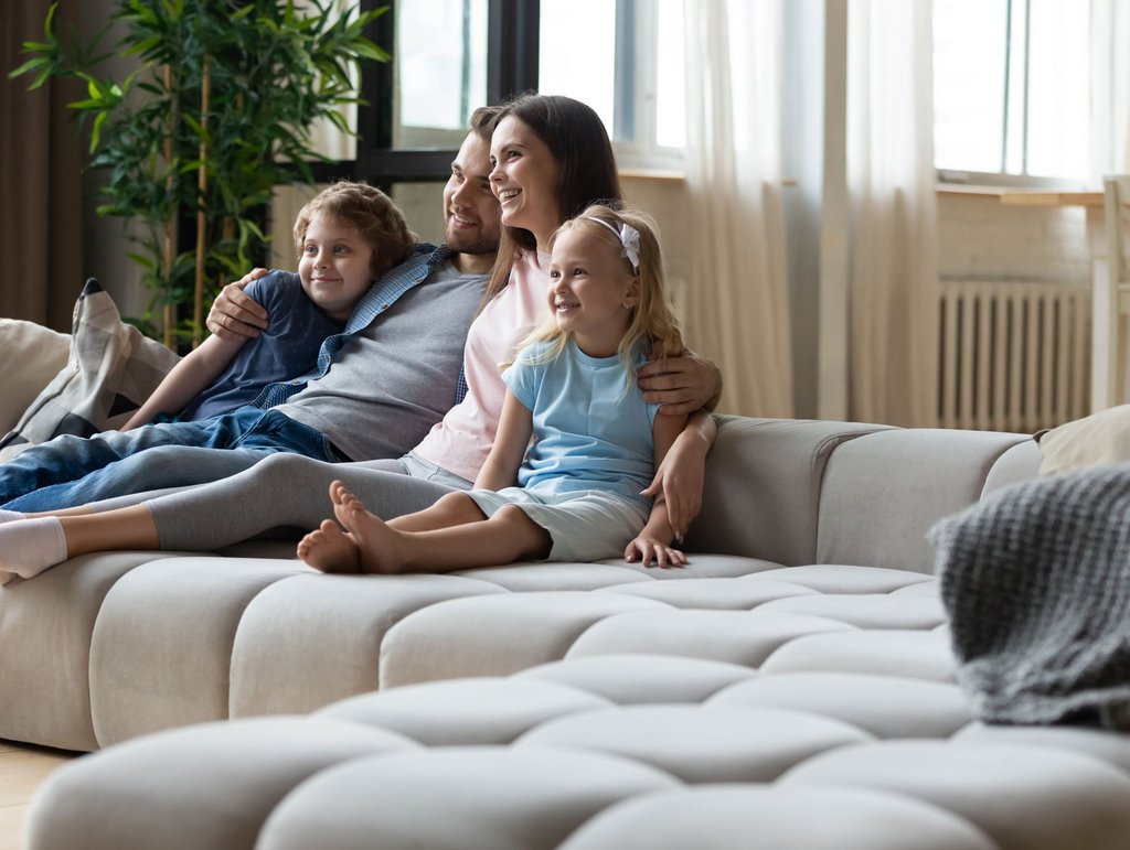 Mann und Frau mit 2 Kindern sitzen auf dem Sofa